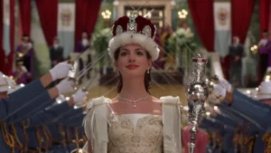 Anne Hathaway como Mia Thermopolis durante cerimônia de coroação em Genovia em cena de O Diário da Princesa 2, simulando a personagem como rainha em O Diário da Princesa 3.