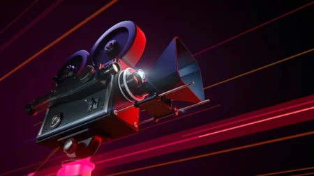 A imagem mostra um projetor de filmes com cores em vermelho e preto