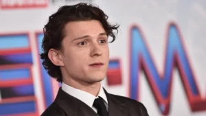 Tom Holland alcança feito inédito ao estar nas maiores estreias do cinema; entenda Tom Holland posa durante evento de divulgação da franquia Homem-Aranha usando terno preto e gravata.