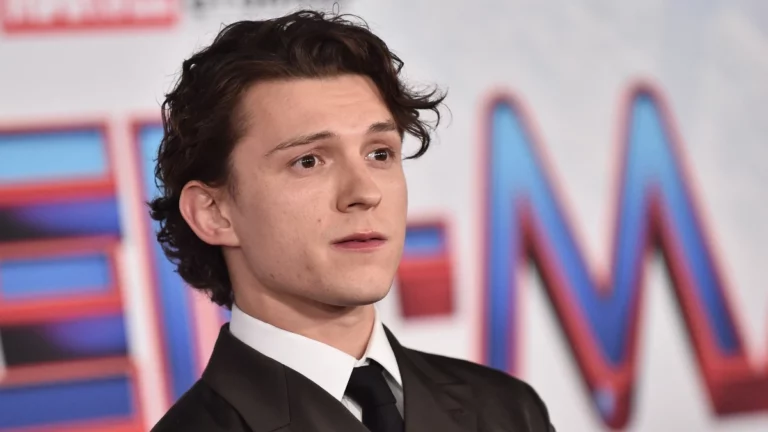 Tom Holland posa durante evento de divulgação da franquia Homem-Aranha usando terno preto e gravata.