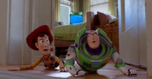 Woody e Buzz aparecem assustados no chão do quarto de Bonnie, enquanto o tablet LilyPad observa os brinquedos ao fundo
