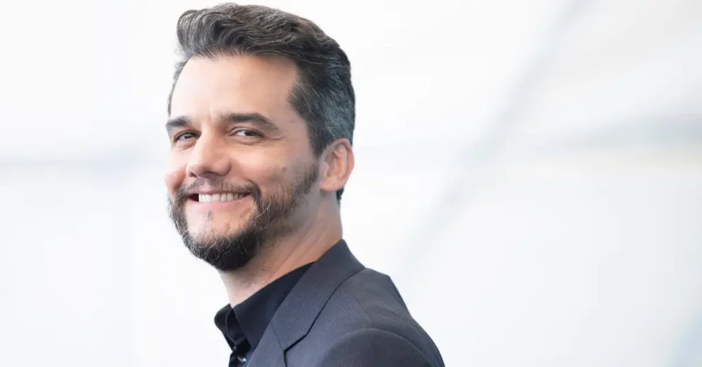 Wagner Moura surge de bigode para thriller vampiresco com Kristen Stewart; confira Wagner Moura sorri usando terno escuro durante aparição pública em evento.