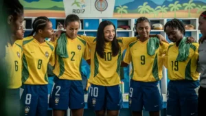 Alice Carvalho caracterizada como Marta reúne jogadoras da Seleção Brasileira em cena da cinebiografia ambientada em um vestiário.