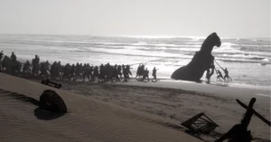 A Odisseia pode superar Oppenheimer na estreia; entenda Equipe puxa uma réplica do Cavalo de Troia pela praia durante as filmagens de A Odisseia