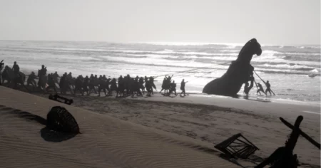 A Odisseia pode superar Oppenheimer na estreia; entenda Equipe puxa uma réplica do Cavalo de Troia pela praia durante as filmagens de A Odisseia
