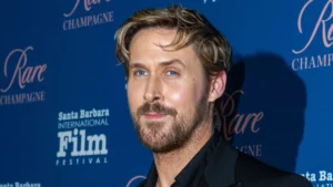 Ryan Gosling posa em evento com fundo azul.