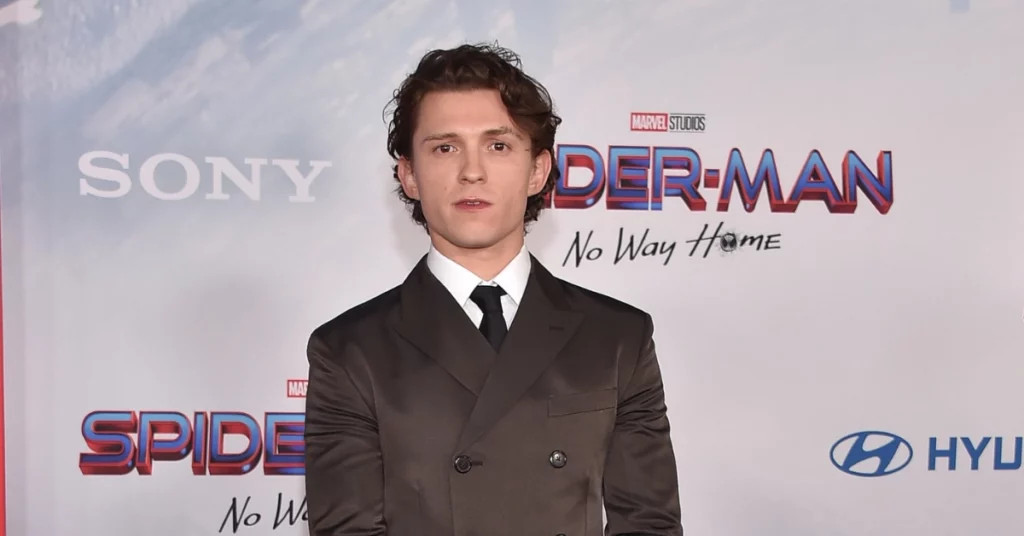 Tom Holland posa de terno preto diante de painel de Homem-Aranha: Sem Volta para Casa