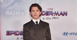 Tom Holland posa de terno preto diante de painel de Homem-Aranha: Sem Volta para Casa