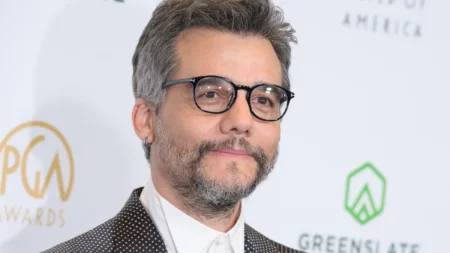 Wagner Moura com barba grisalha e óculos em evento.