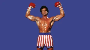 Sylvester Stallone revela uso de esteroides e bulimia ao viver Rocky: ‘Obsessão’ Sylvester Stallone interpreta Rocky Balboa e aparece sem camisa, com o corpo musculoso e os braços erguidos usando luvas de boxe.