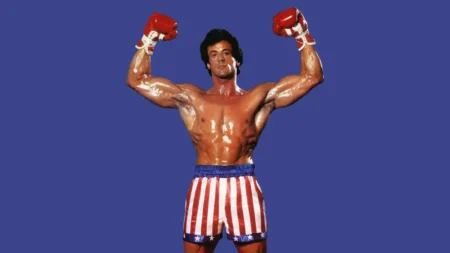 Sylvester Stallone revela uso de esteroides e bulimia ao viver Rocky: ‘Obsessão’ Sylvester Stallone interpreta Rocky Balboa e aparece sem camisa, com o corpo musculoso e os braços erguidos usando luvas de boxe.